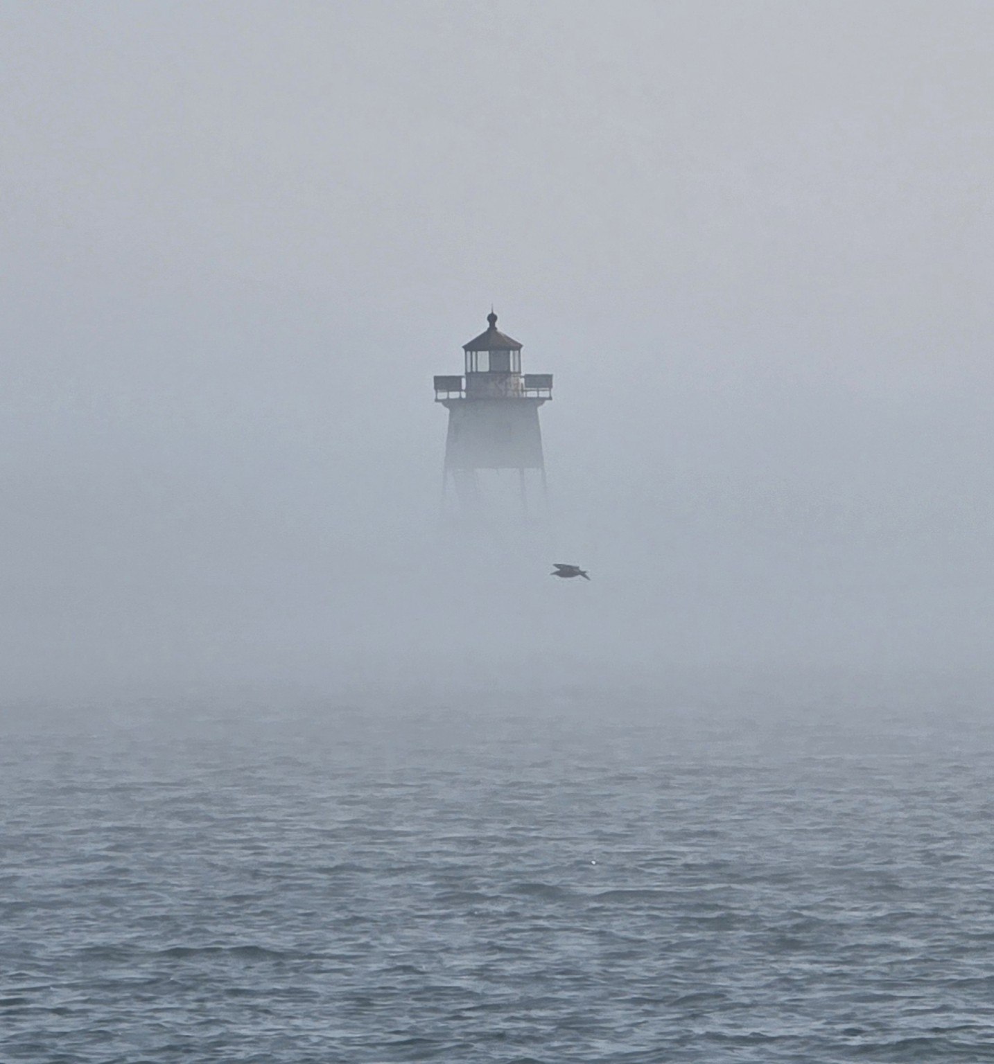 Lighthouse emerging through fog over Lake Superior