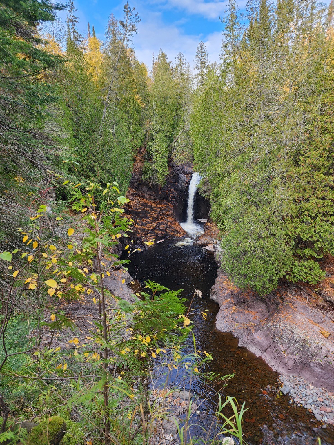 Waterfall flowing through a forested gorge
